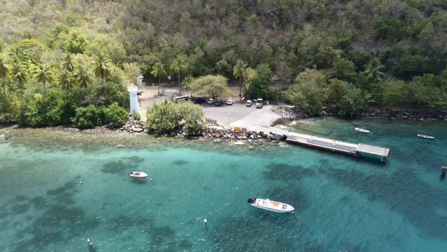 Ponton, phare et eaux turquoises d'une anse de la côte caraïbe, vue de drone