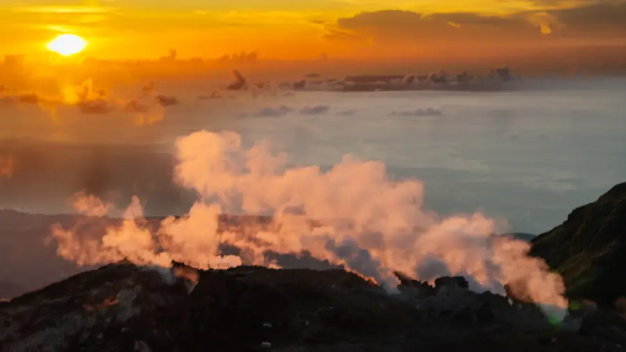 Fumerolles de la Soufrière éclairées par le soleil levant, la mer des Caraïbes à l'horizon