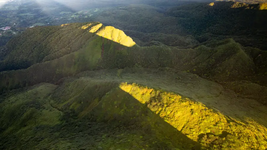 Mornes verdoyants au pied de la Soufrière, éclairés par le soleil